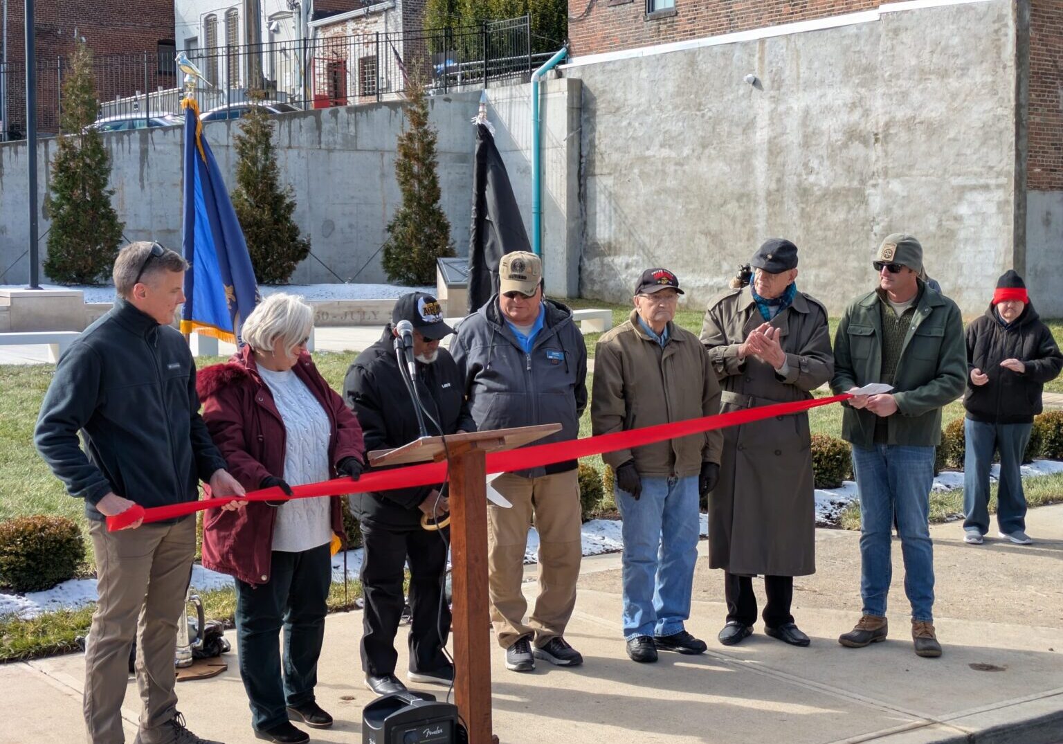 Veterans Council members David Ward, Dianna Layne, Greg Yates, Don Rose, Chuck Witt, and Dee Birkes watching as Council President Roy Hudson did the honors of cutting the red ribbon to officially open the memorial.